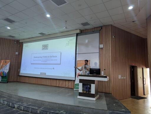 A speaker on stage at conf.kde.in. The title on his first slide says: "Embracing FOSS in EdTech".